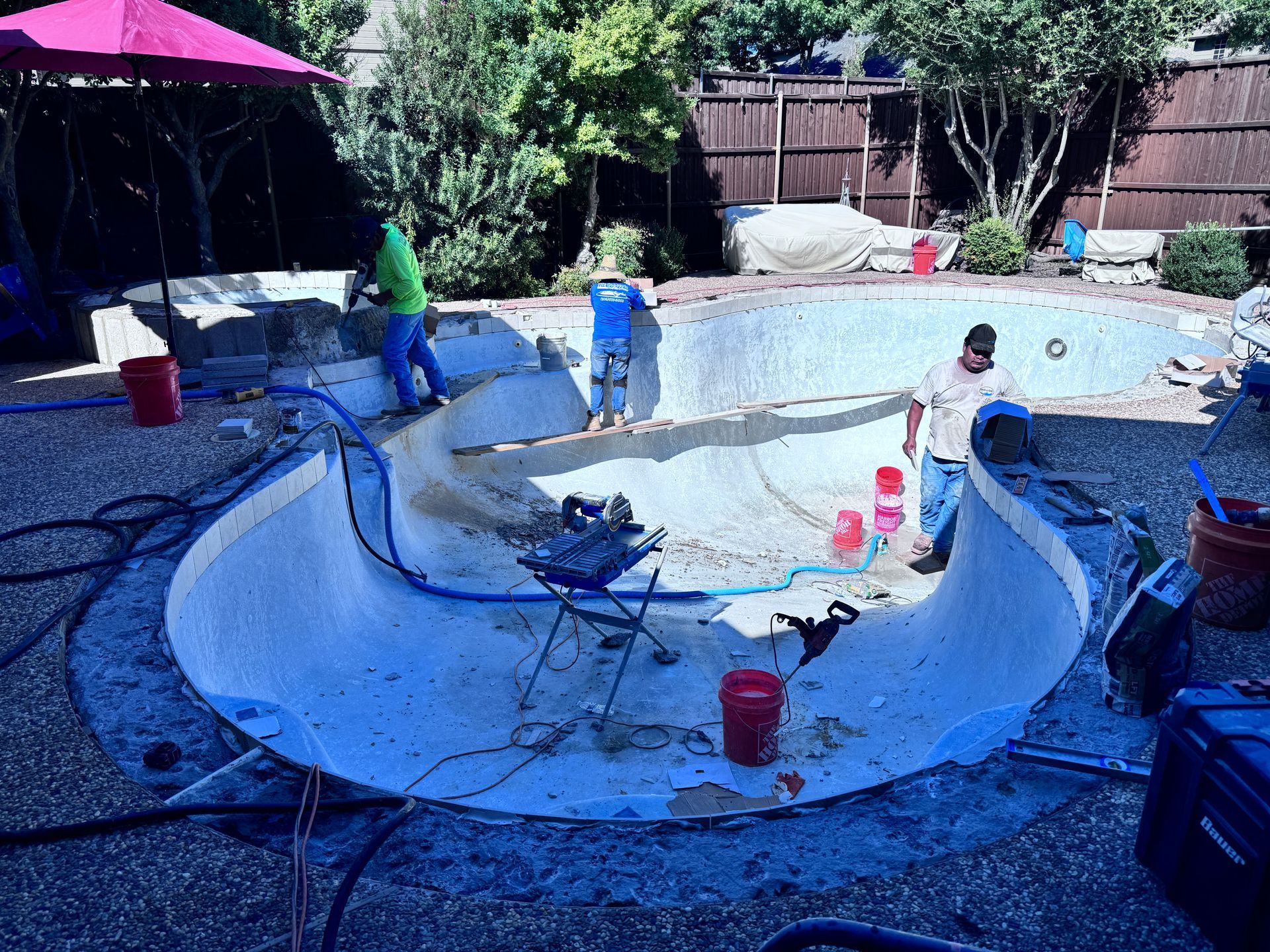 A man is working on a swimming pool in a backyard.