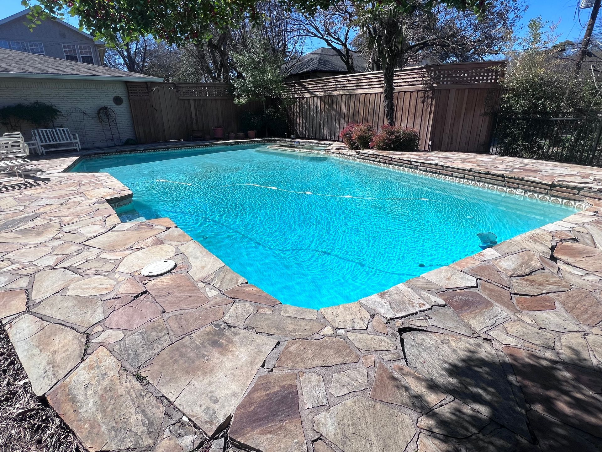 There is a large swimming pool in the backyard of a house.