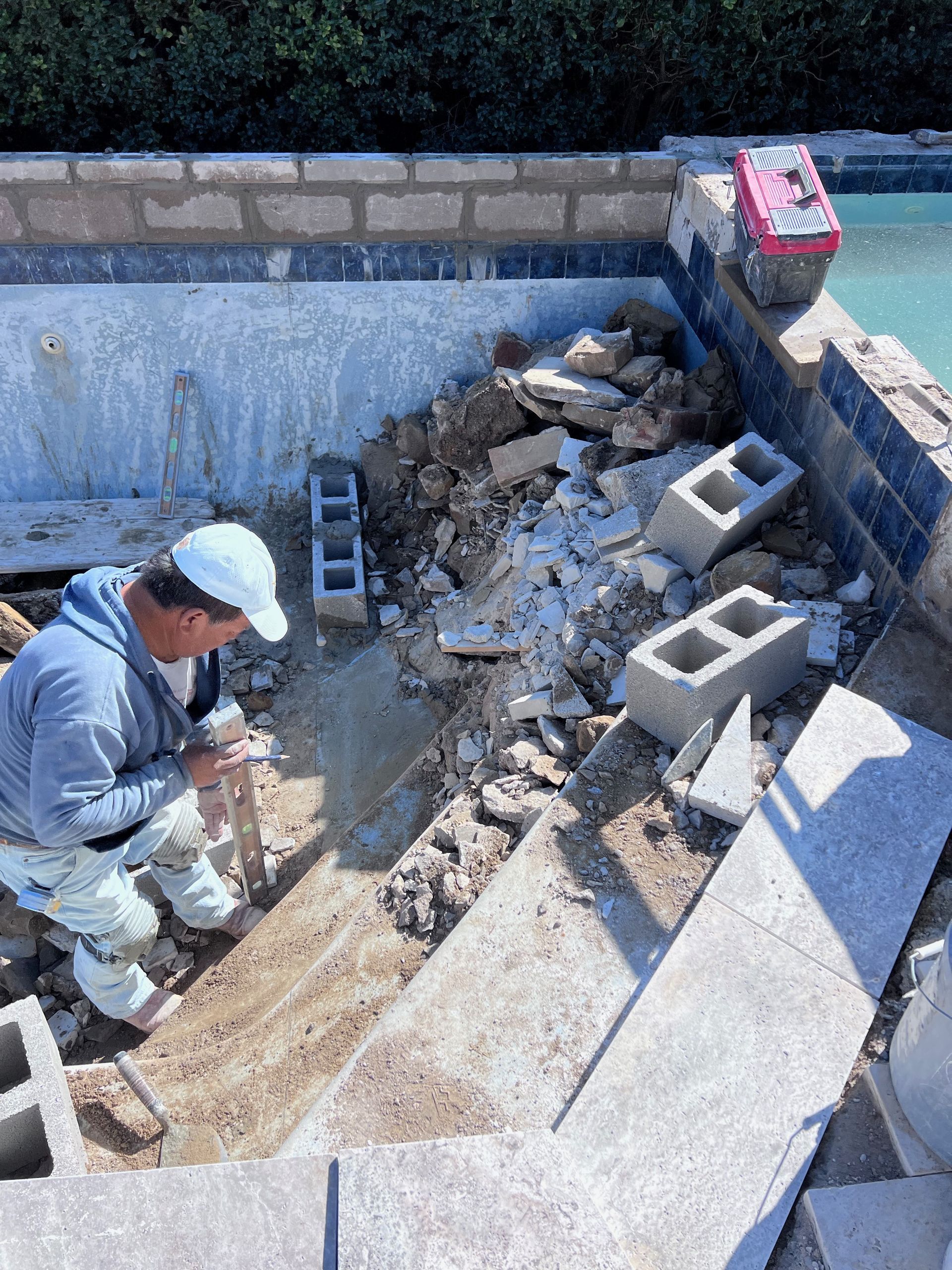 A man is working on a staircase next to a pool.