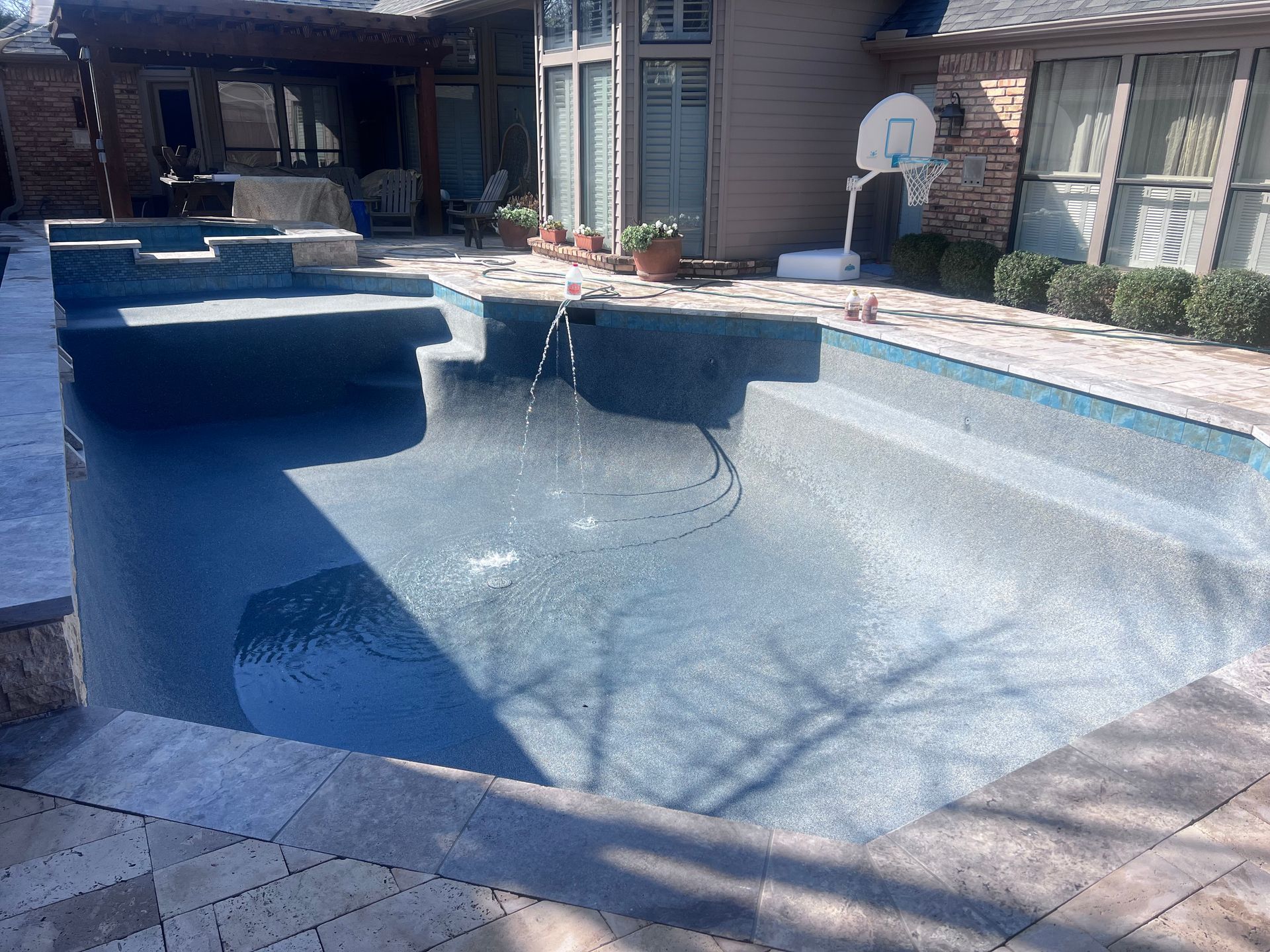 A large swimming pool is in the backyard of a house.
