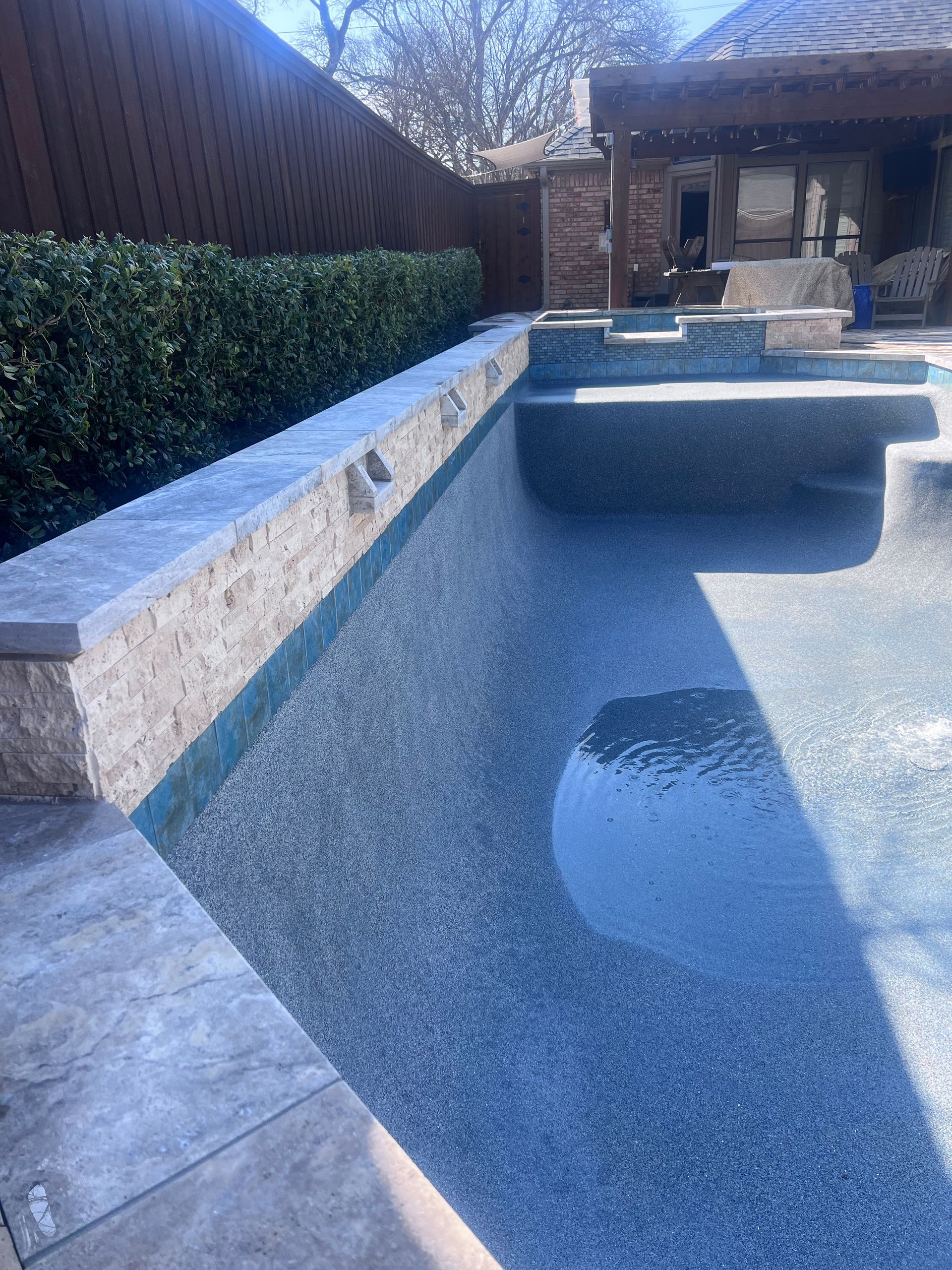 A large swimming pool with a stone wall surrounding it.