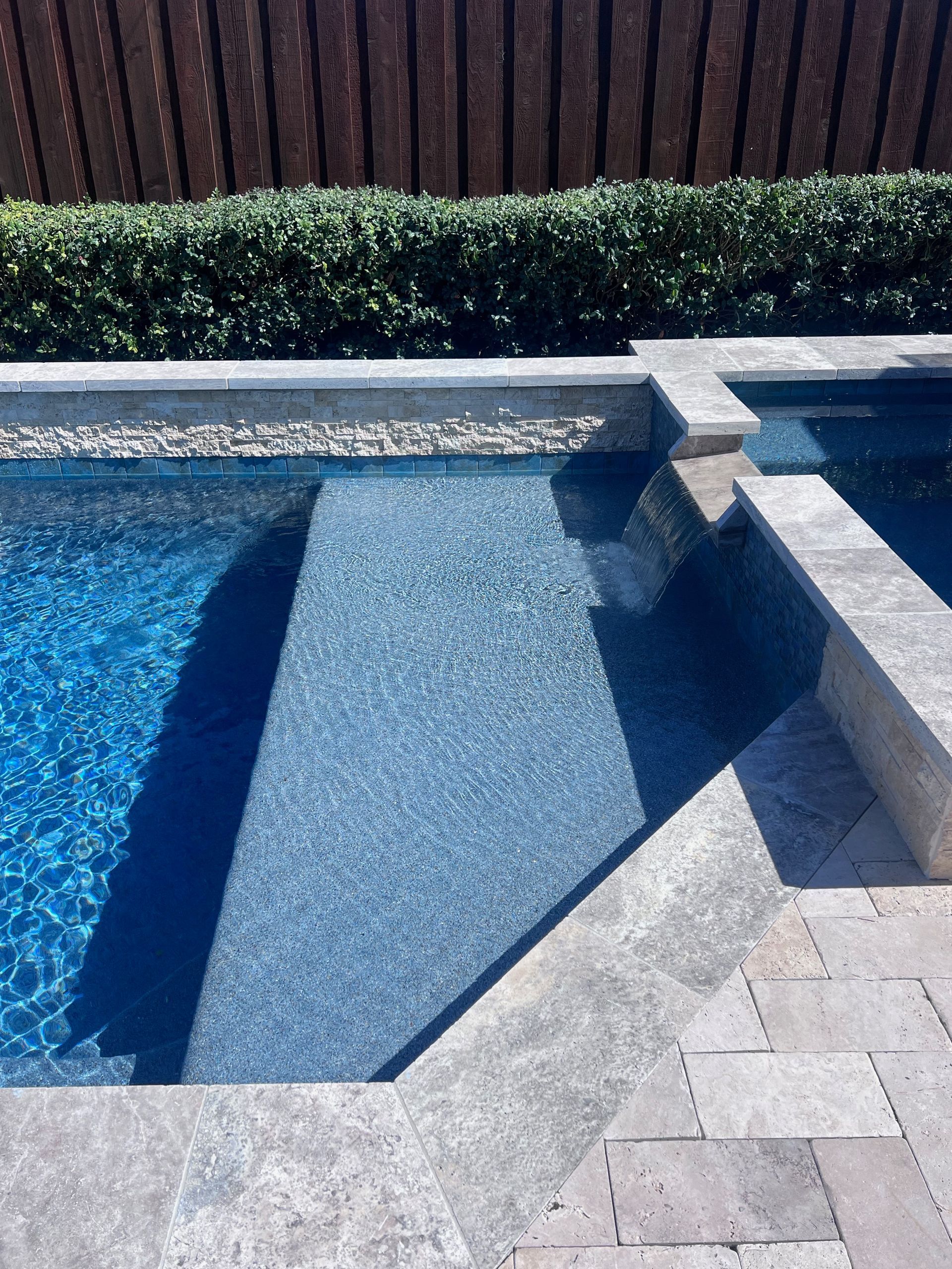 A swimming pool with a wooden fence in the background