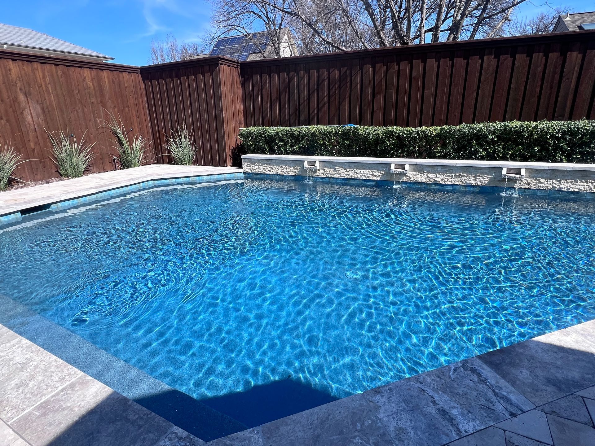 A large swimming pool with a wooden fence in the background.