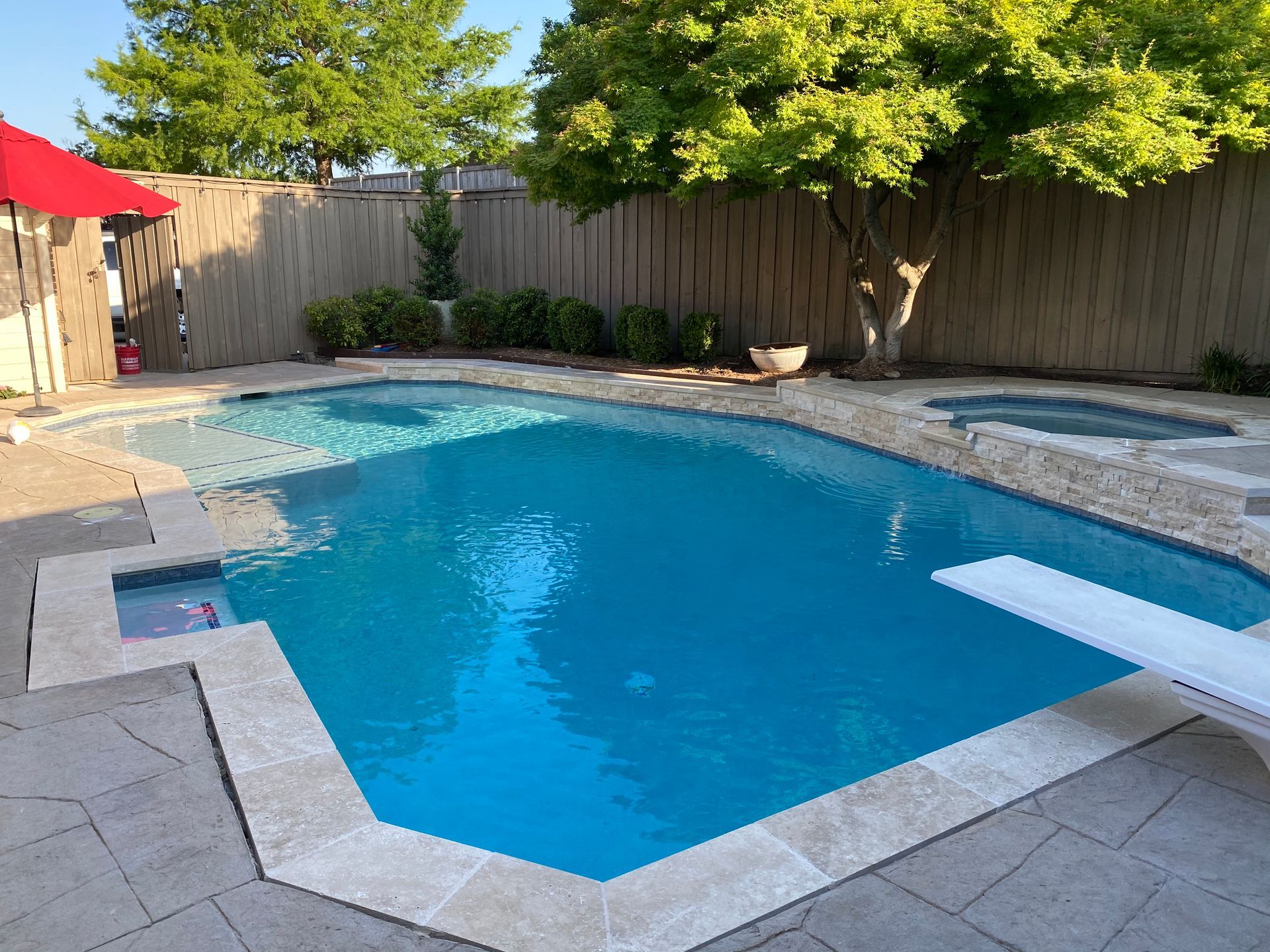 A large swimming pool with a red umbrella in the background
