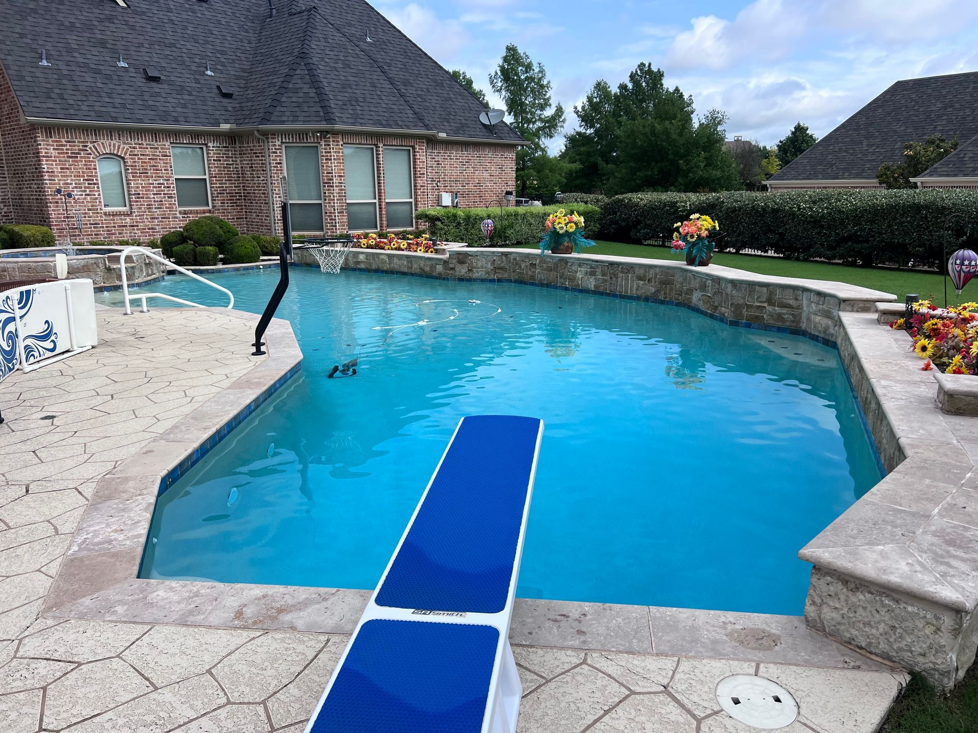 A large swimming pool with a diving board in front of a house.