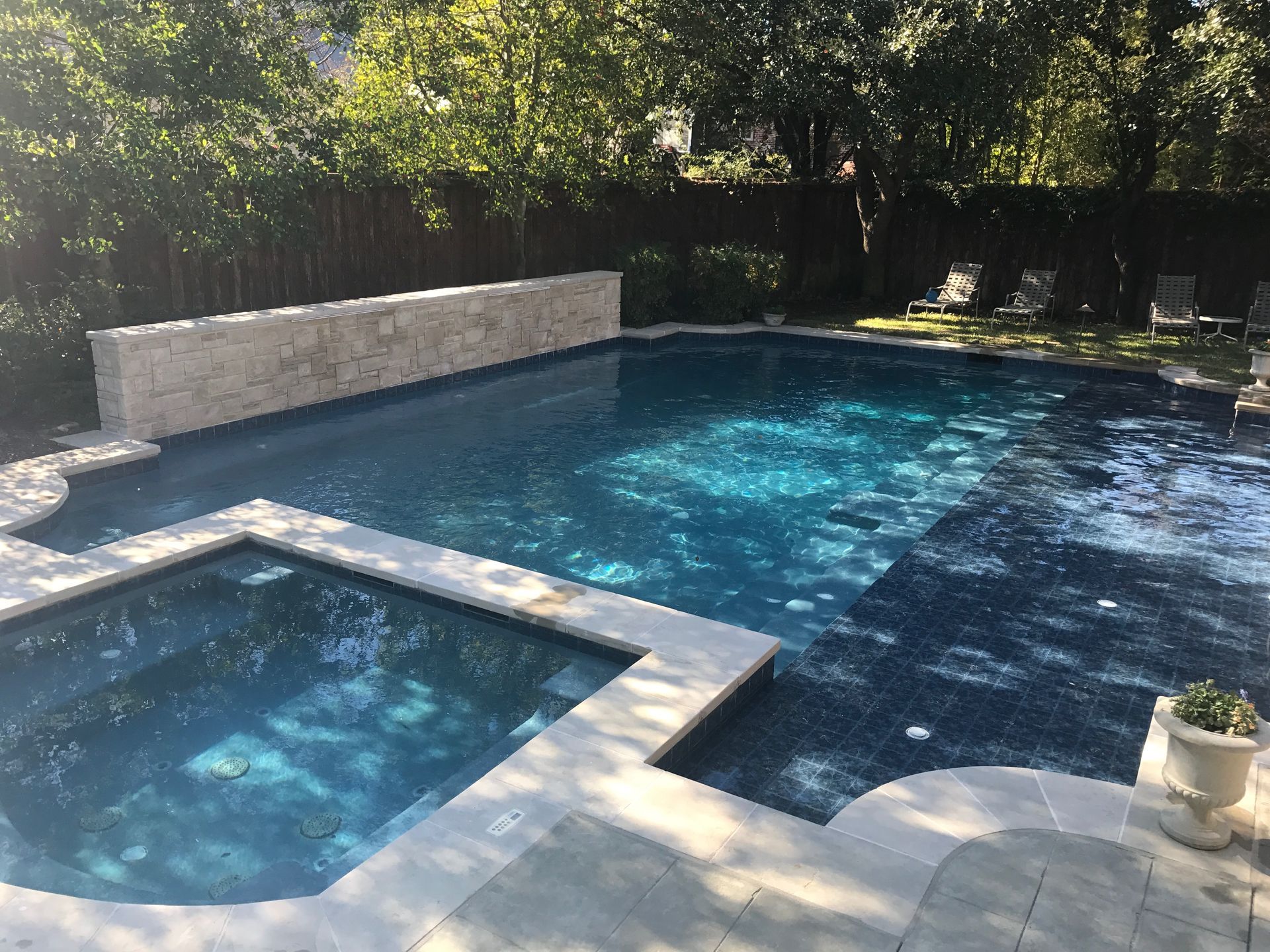 A large swimming pool with a hot tub in the backyard