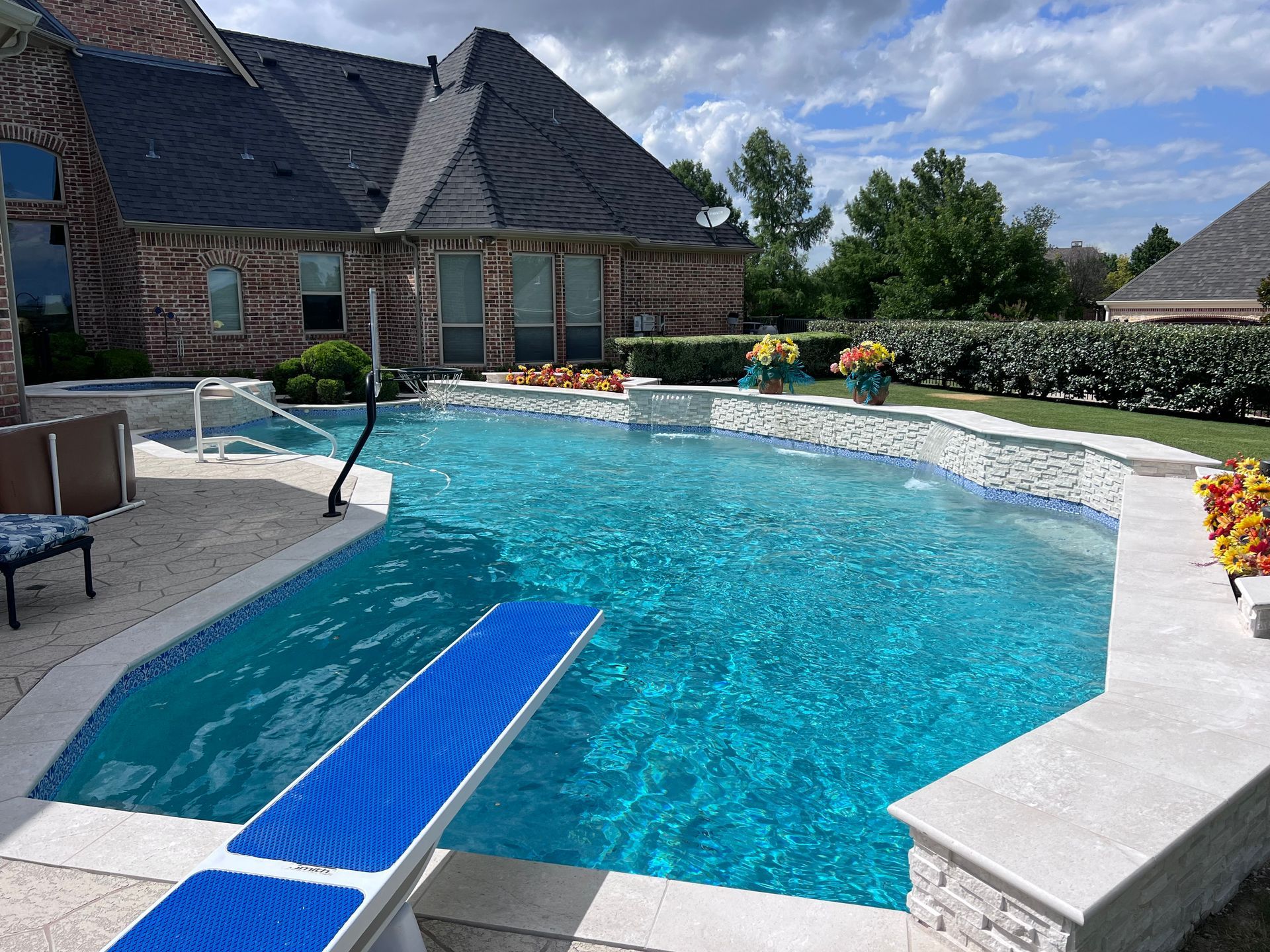 A large swimming pool is surrounded by a brick house.