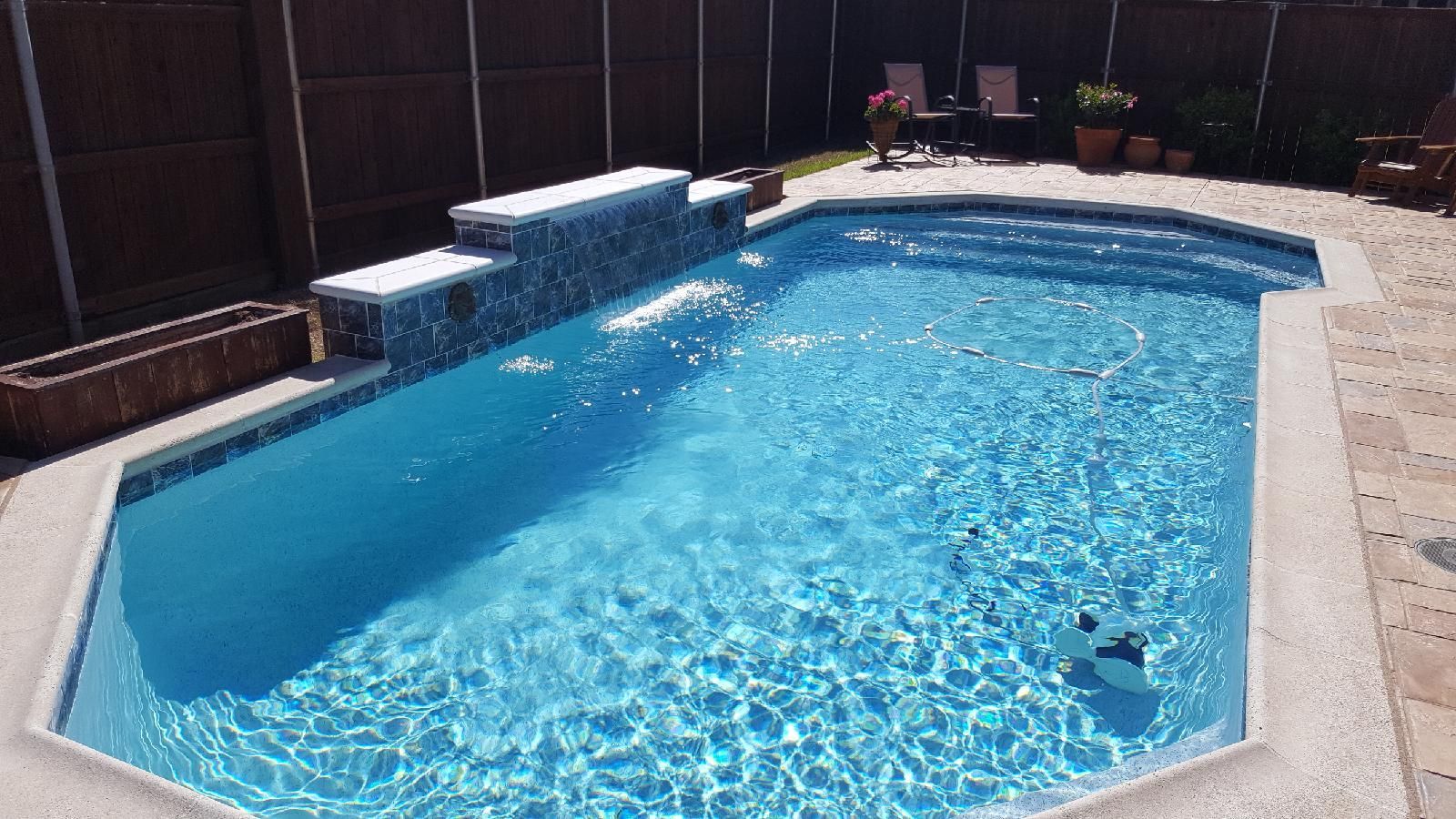 A large swimming pool filled with blue water in a backyard.