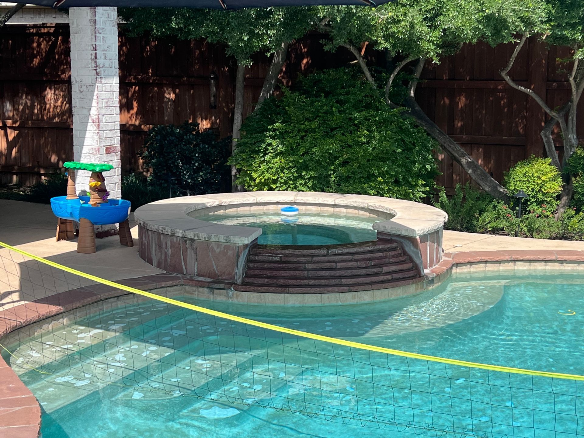 A swimming pool with a hot tub in the middle of it