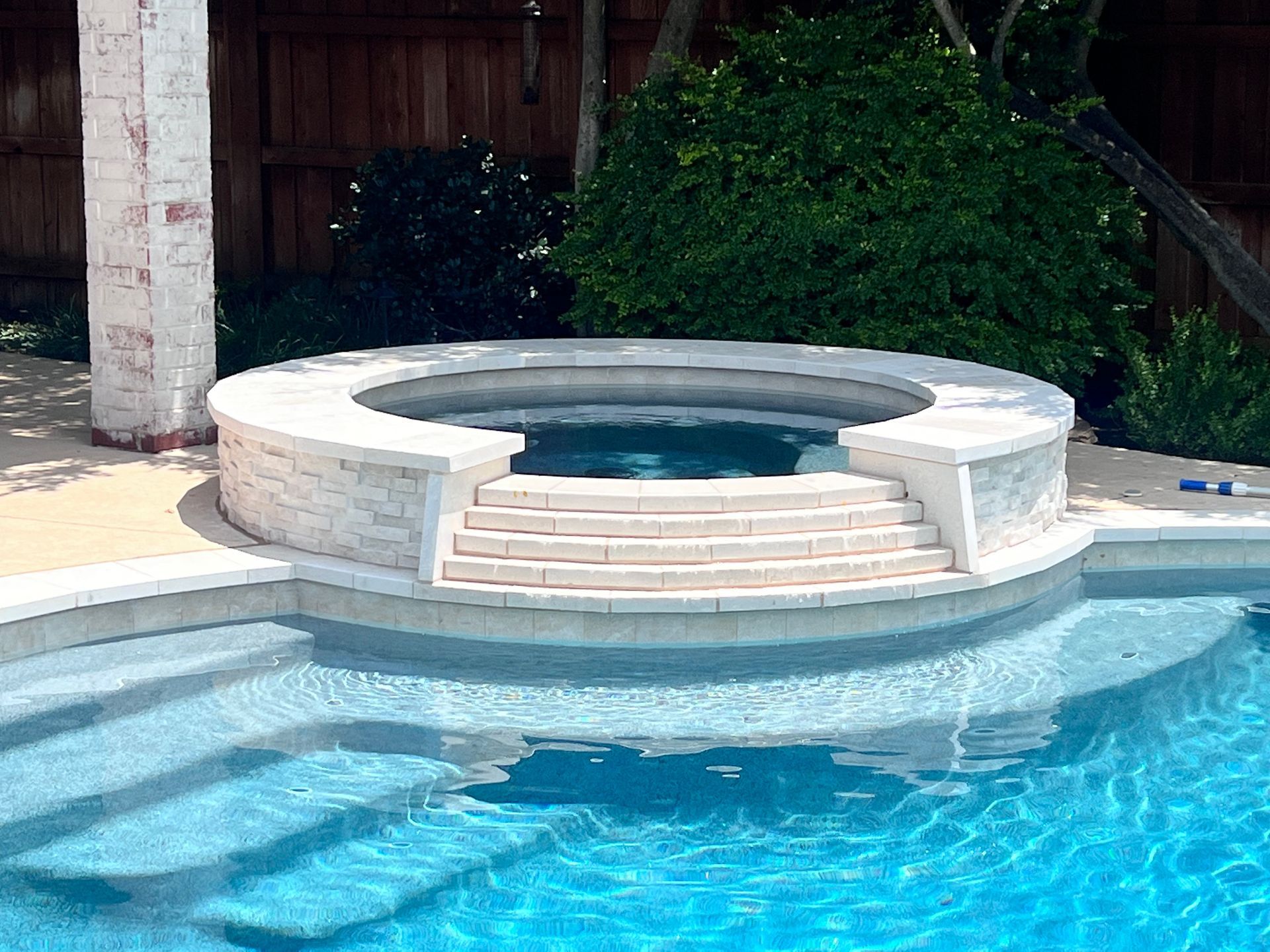 A swimming pool with stairs and a hot tub in the middle