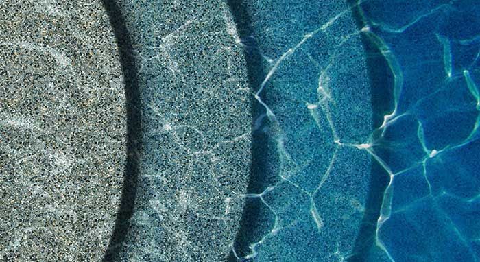 A close up of a swimming pool with different colored tiles and water.