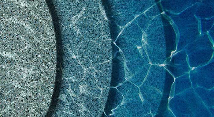A close up of a swimming pool with steps and a blue water surface.