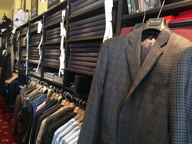 A row of suits are hanging in a store