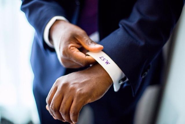 A man in a suit and tie is adjusting his cufflinks.