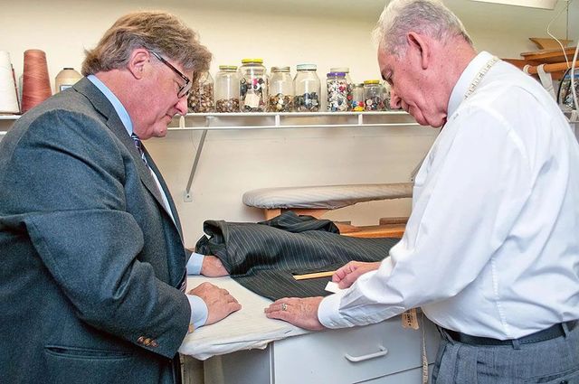 Two men are looking at a piece of clothing on an ironing board.
