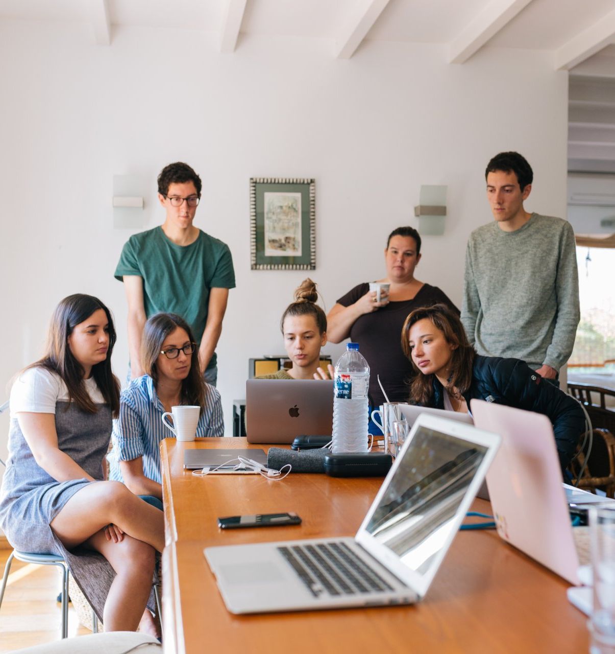 A group of people are sitting around a table looking at laptops