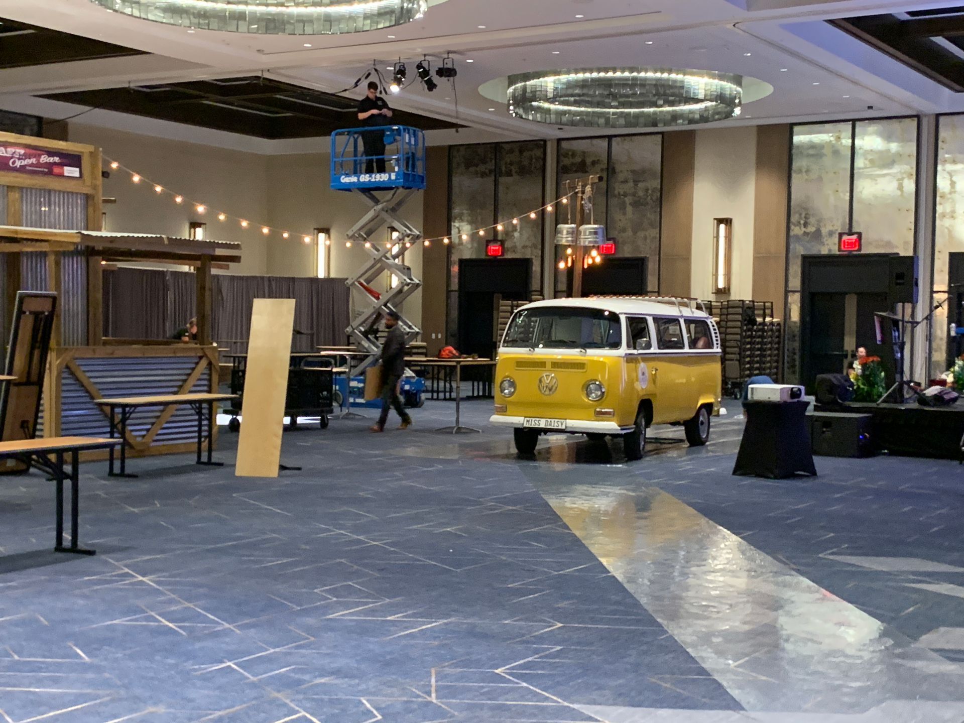 A yellow VW bus from SunKissed Photo Bus is pushed through the JW Marriott ballroom, rolling on a plastic drop cloth