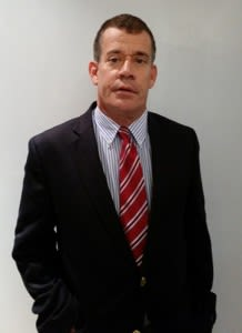 a man in a suit and tie is standing with his hands in his pockets .