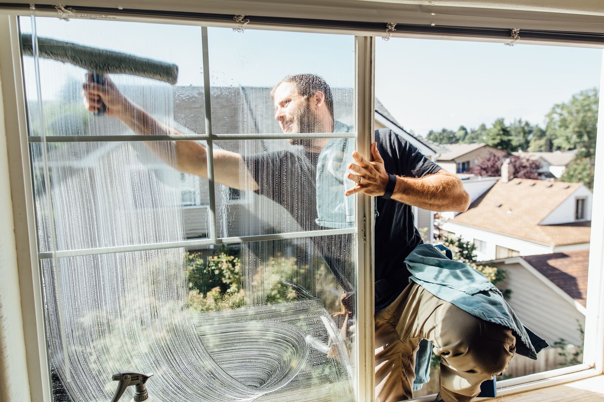 Worker washing the outside of a second-story window with a squeegee, viewed from inside the room Worker washing the outside of a second-story window with a squeegee, viewed from inside the room