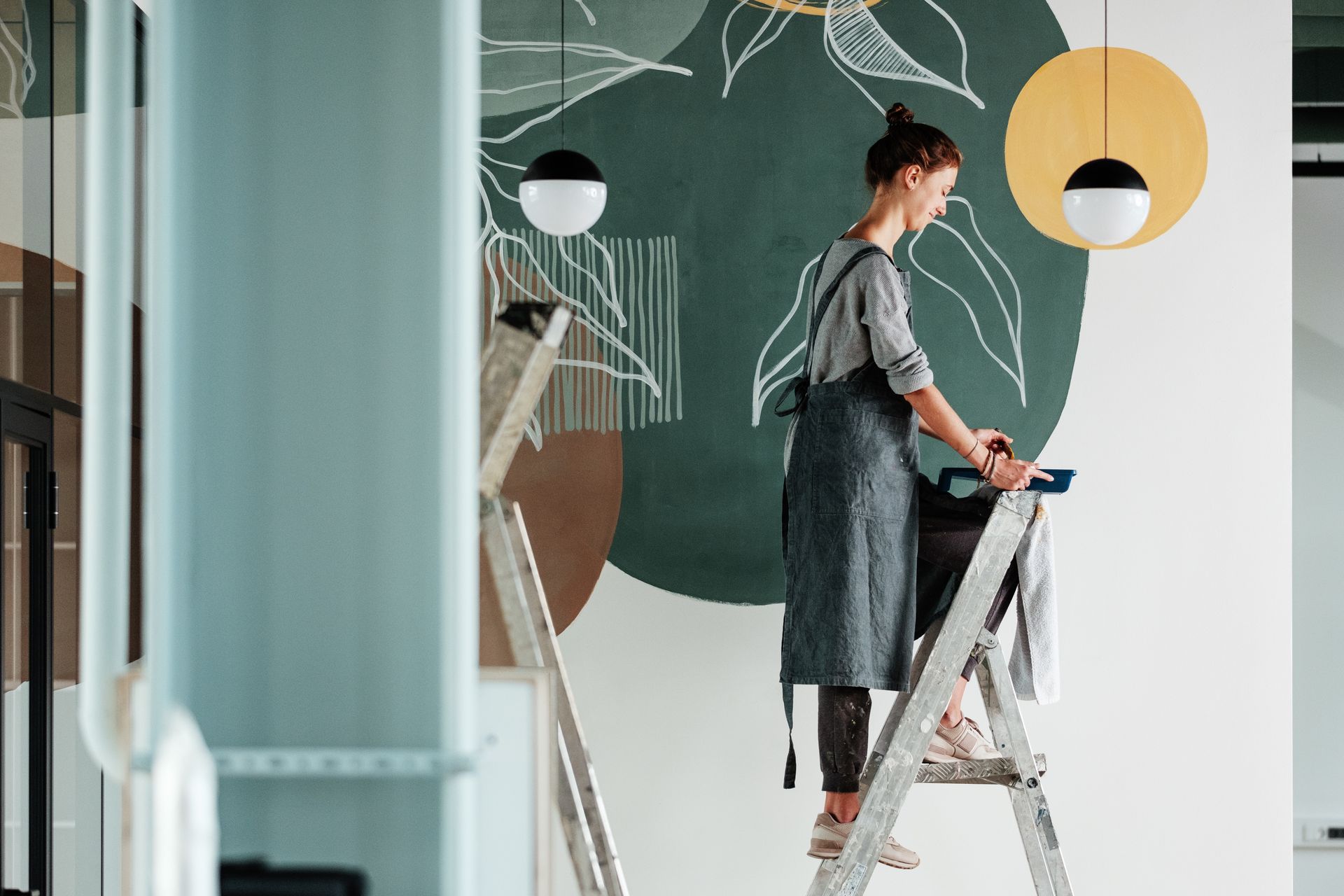Person painting a wall with chalkboard-style mural in a bright room Person painting a wall with chalkboard-style mural in a bright room