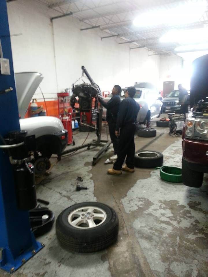 Auto repair shop with mechanic working near a raised car and a tire on the floor