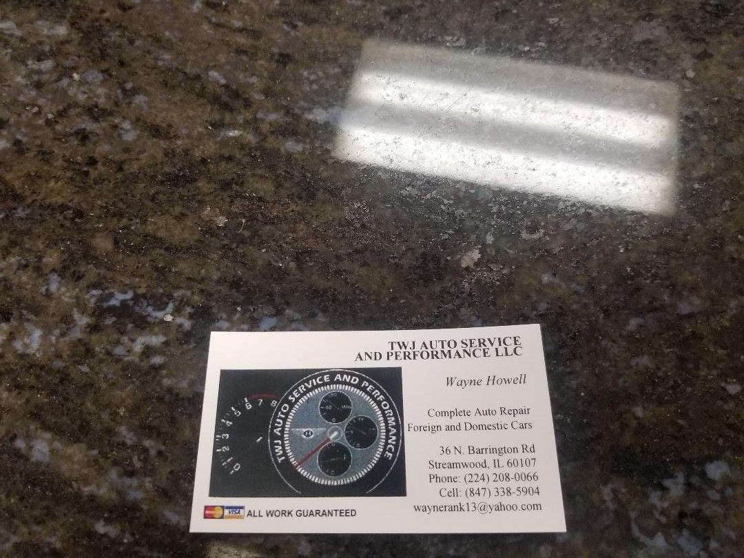 Business card on a dark countertop, with a circular logo and small text beside it.