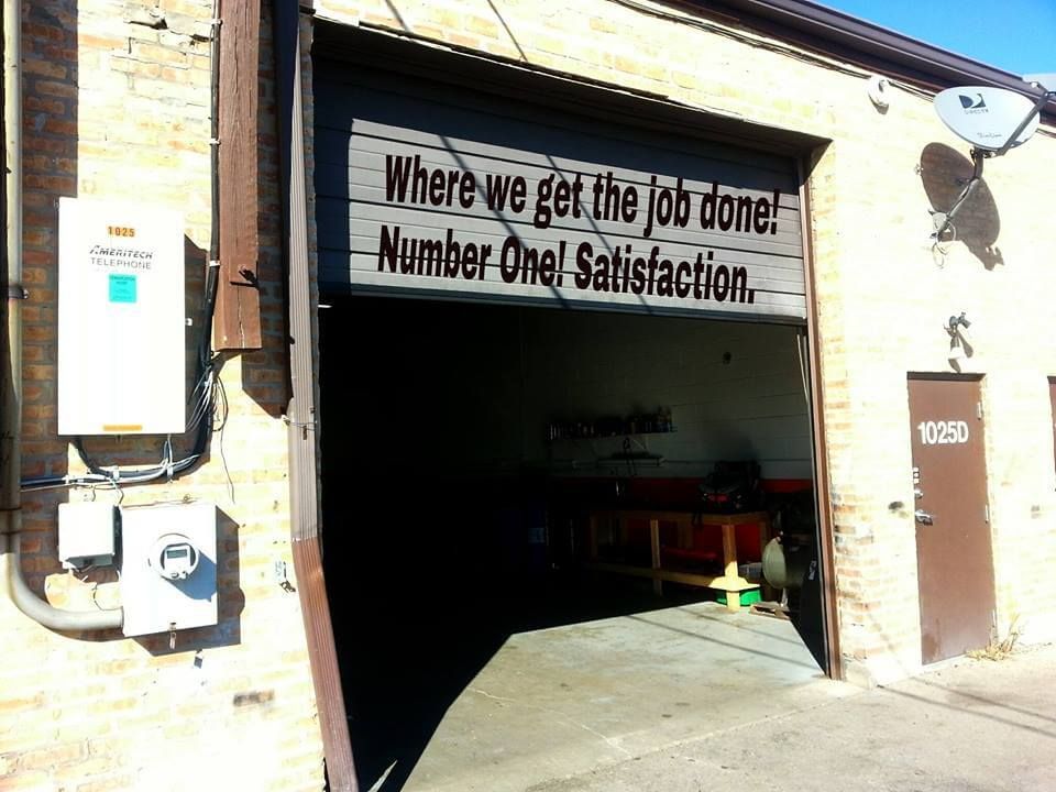 Garage bay with sign reading “Where we get the job done. Number One! Satisfaction.”