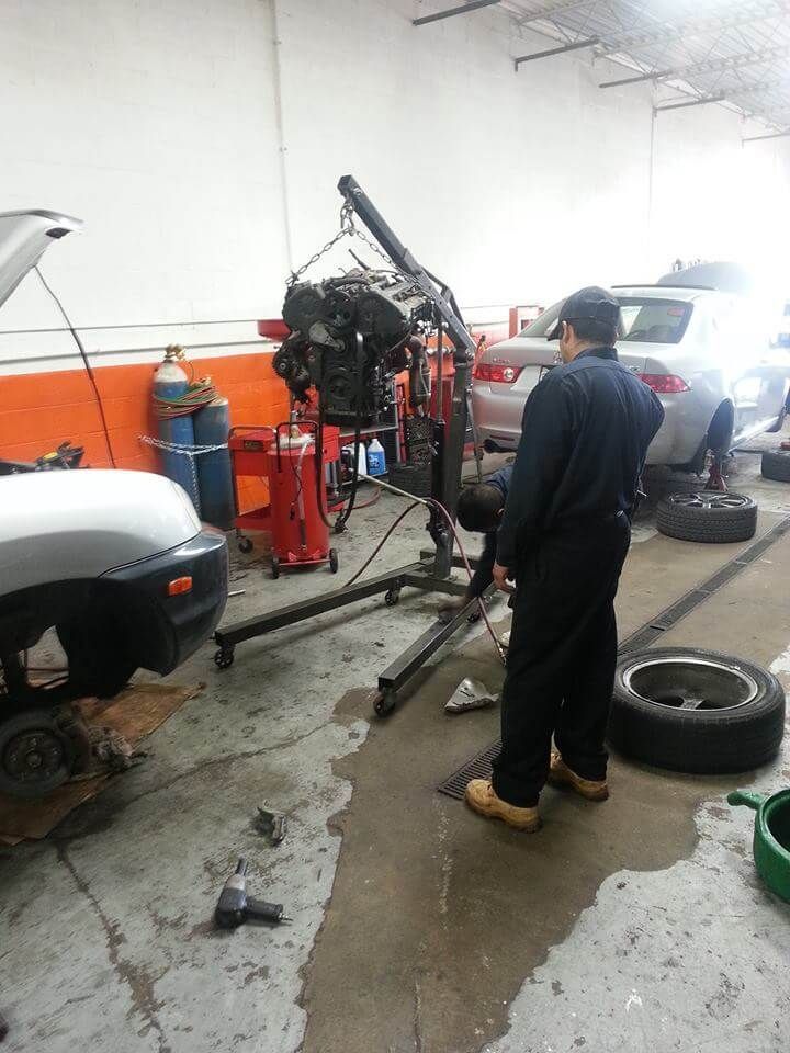 Mechanic in a garage working on a car engine beside tools and parked vehicles