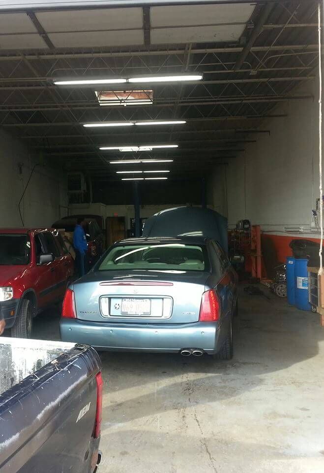 Cars parked inside a garage, including a teal car centered under fluorescent lights.