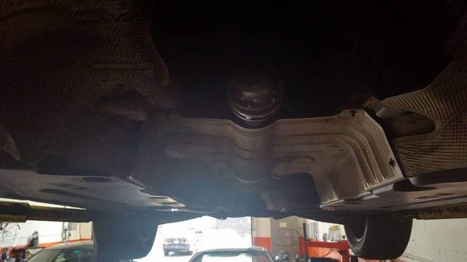 Undercarriage of a car on a lift, showing the exhaust and suspension from below.