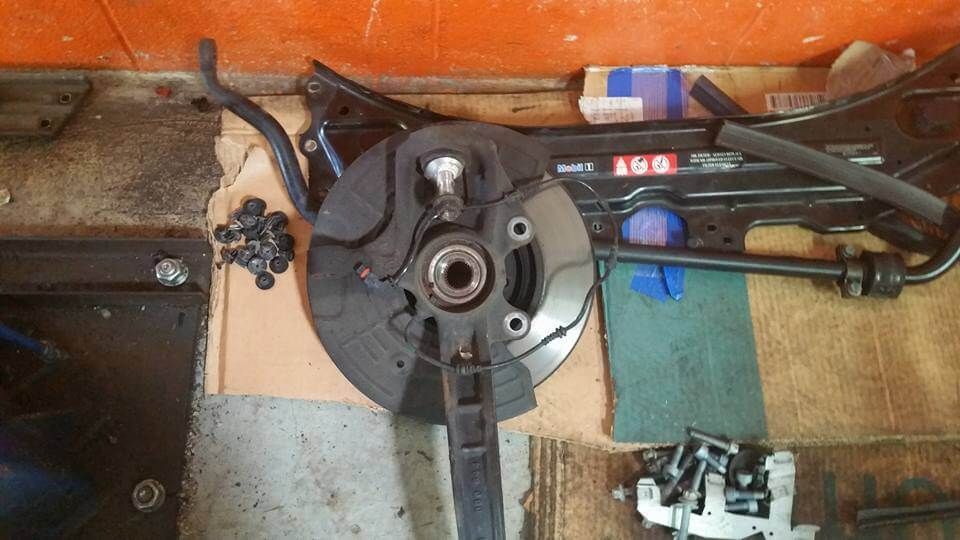 Close-up of a disassembled bicycle crank and chainring on a tiled floor with tools nearby