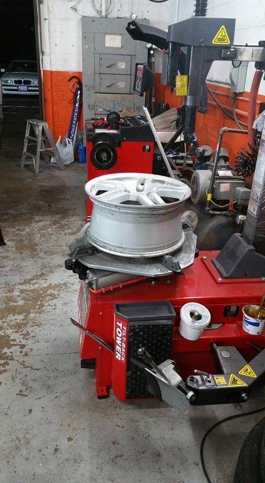 Red tire-changing machine with white wheel rim in a workshop garage.