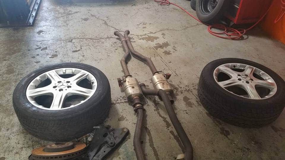 Car parts on a garage floor, including two tires and a detached exhaust system.