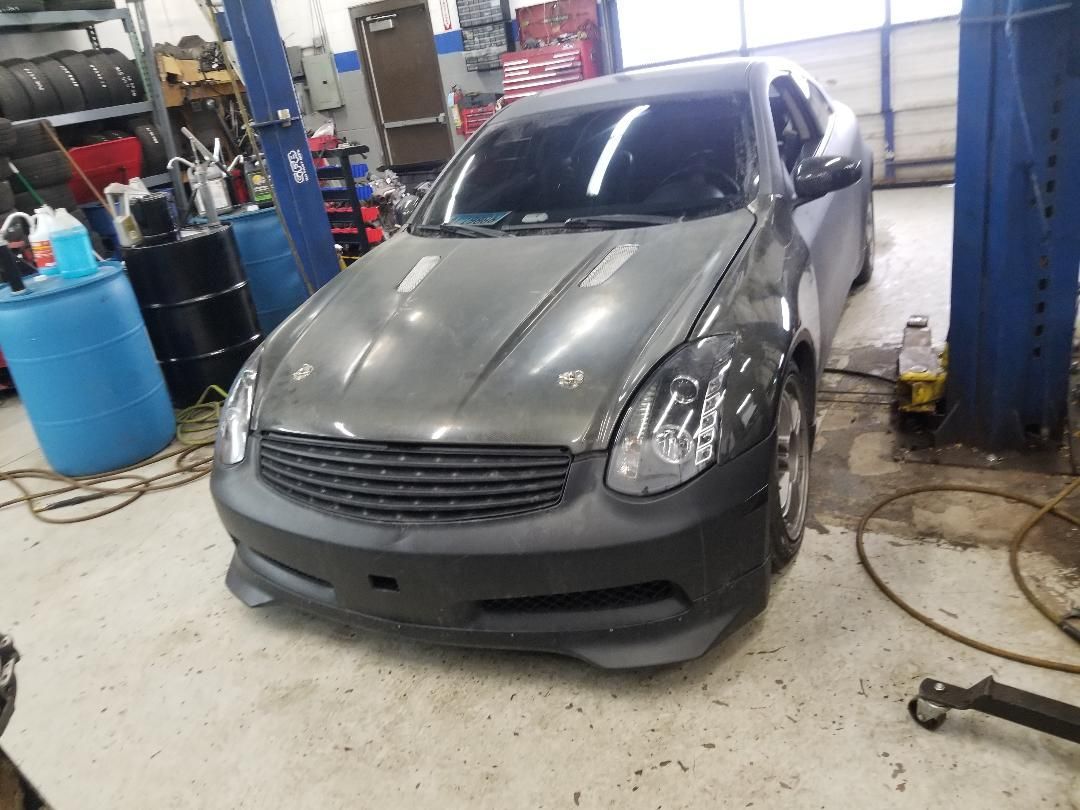 Gray compact car in an auto shop bay with lifts and tools nearby