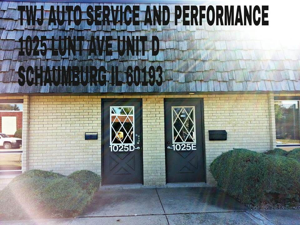 TWI Auto Service and Performance storefront with two doors, tan brick exterior, and trimmed bushes