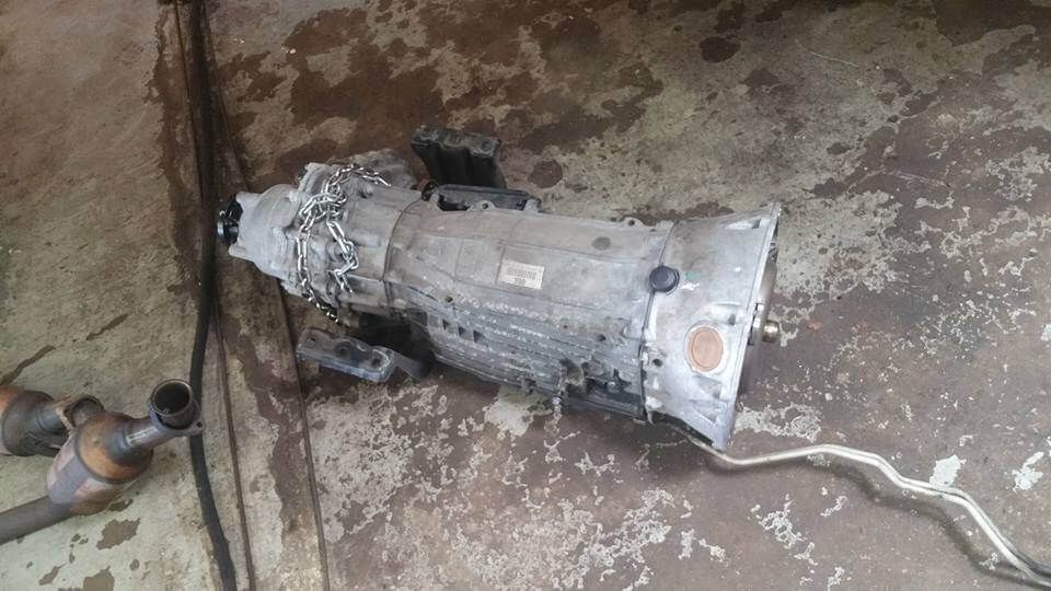 Damaged silver electric appliance lying on a dirty concrete floor with a white cord attached