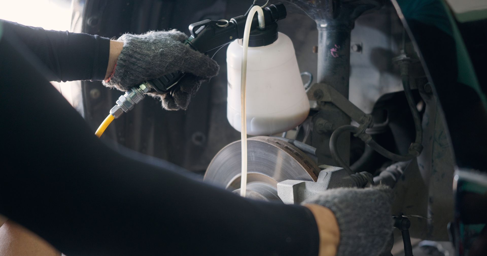 Gloved hands using a circular saw to cut metal in an industrial workshop