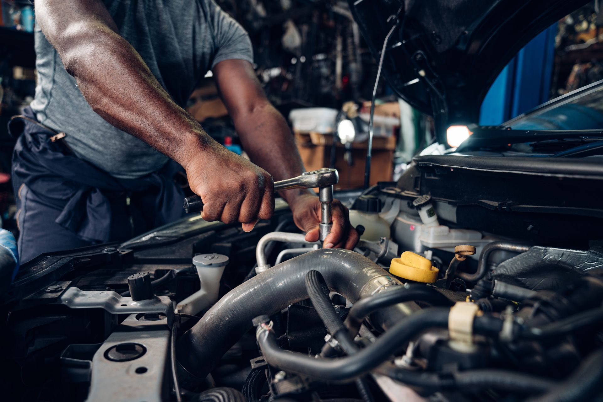 Mechanic using tools to repair a car engine in a workshop