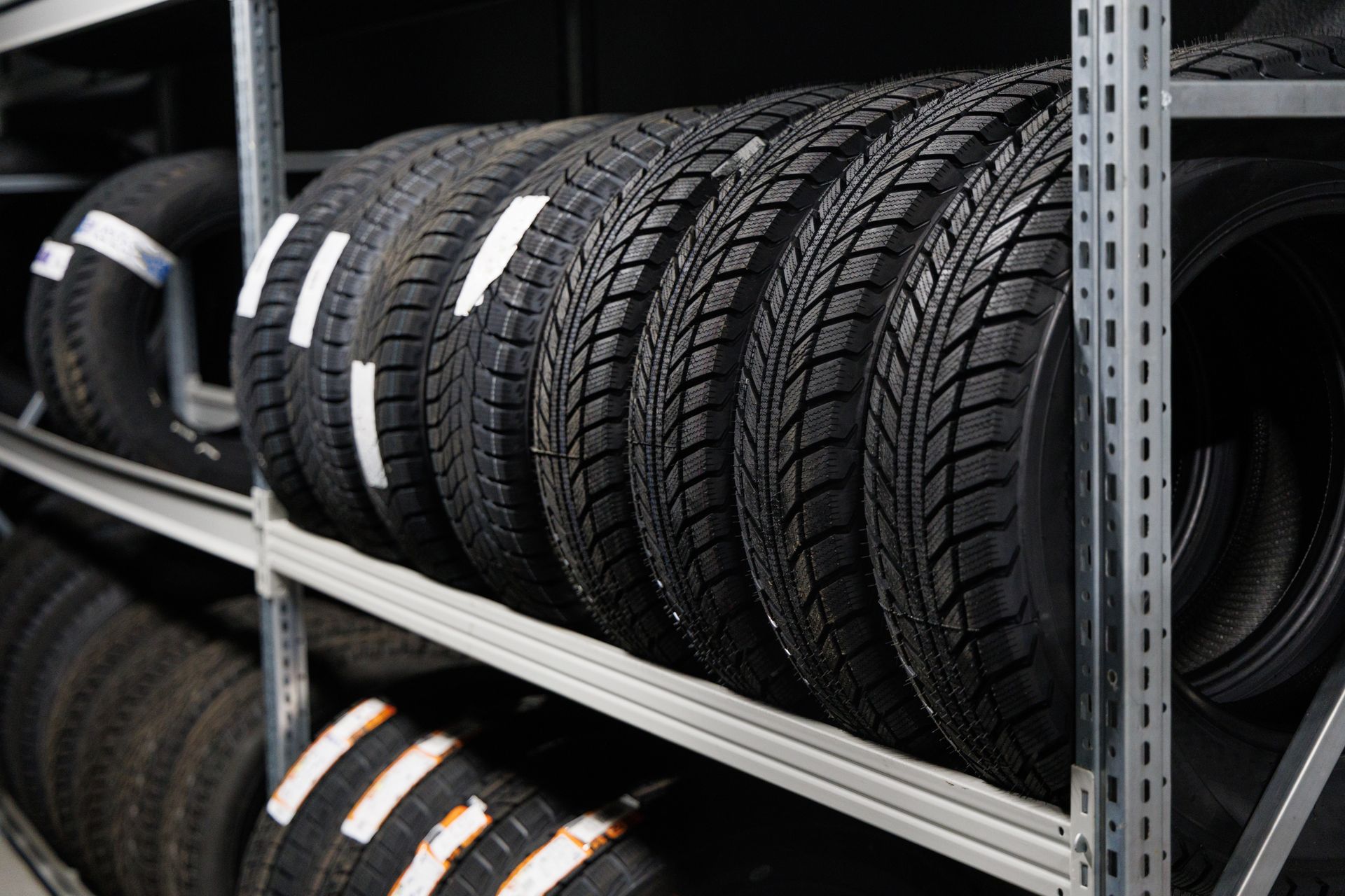 Rows of black car tires stacked on metal warehouse shelves