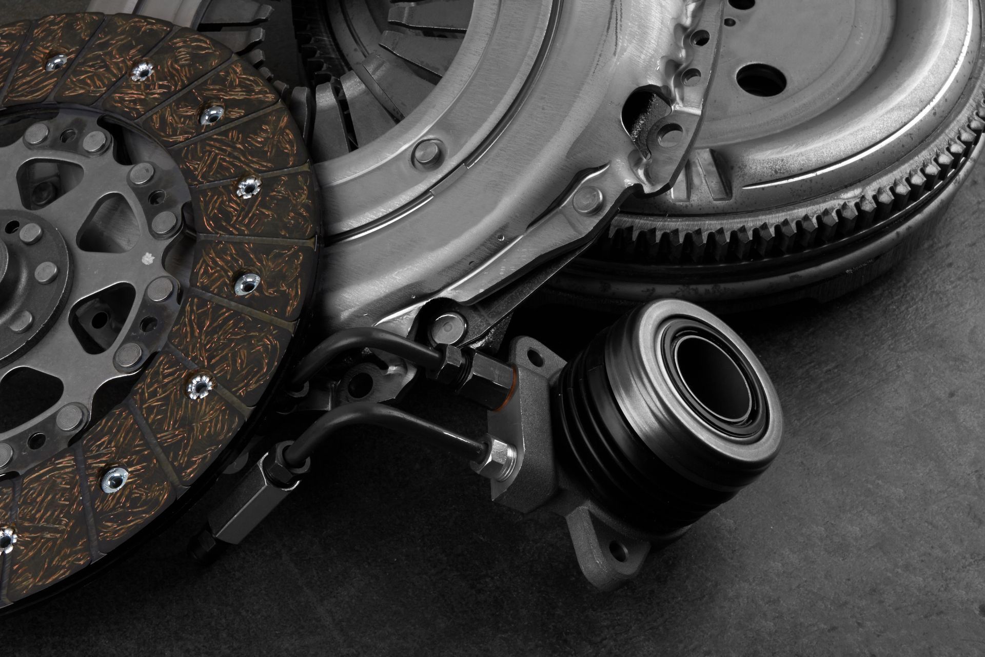 Automotive clutch and flywheel parts laid out on a dark surface