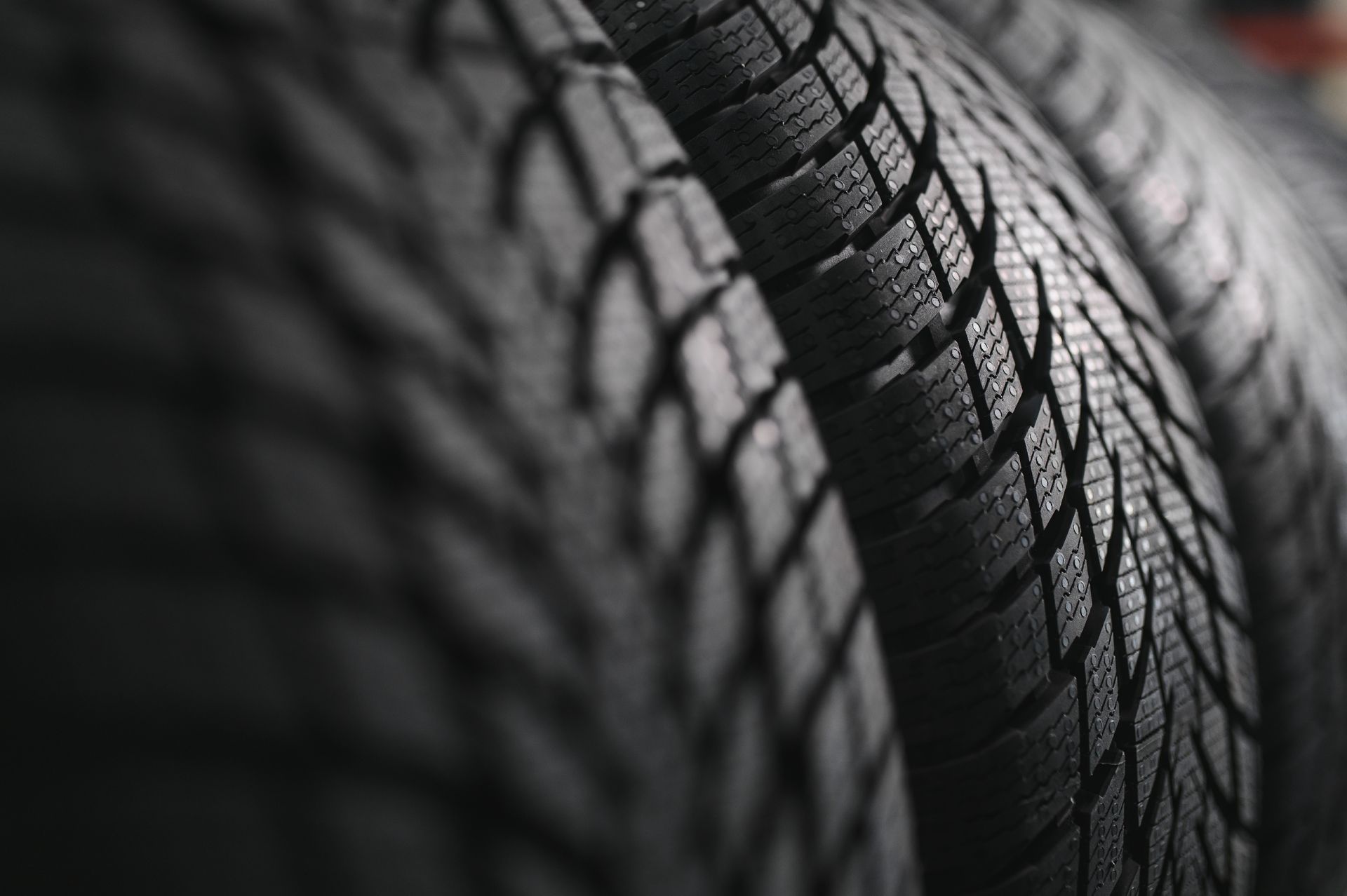 Close-up of stacked black tires with textured tread patterns in monochrome lighting