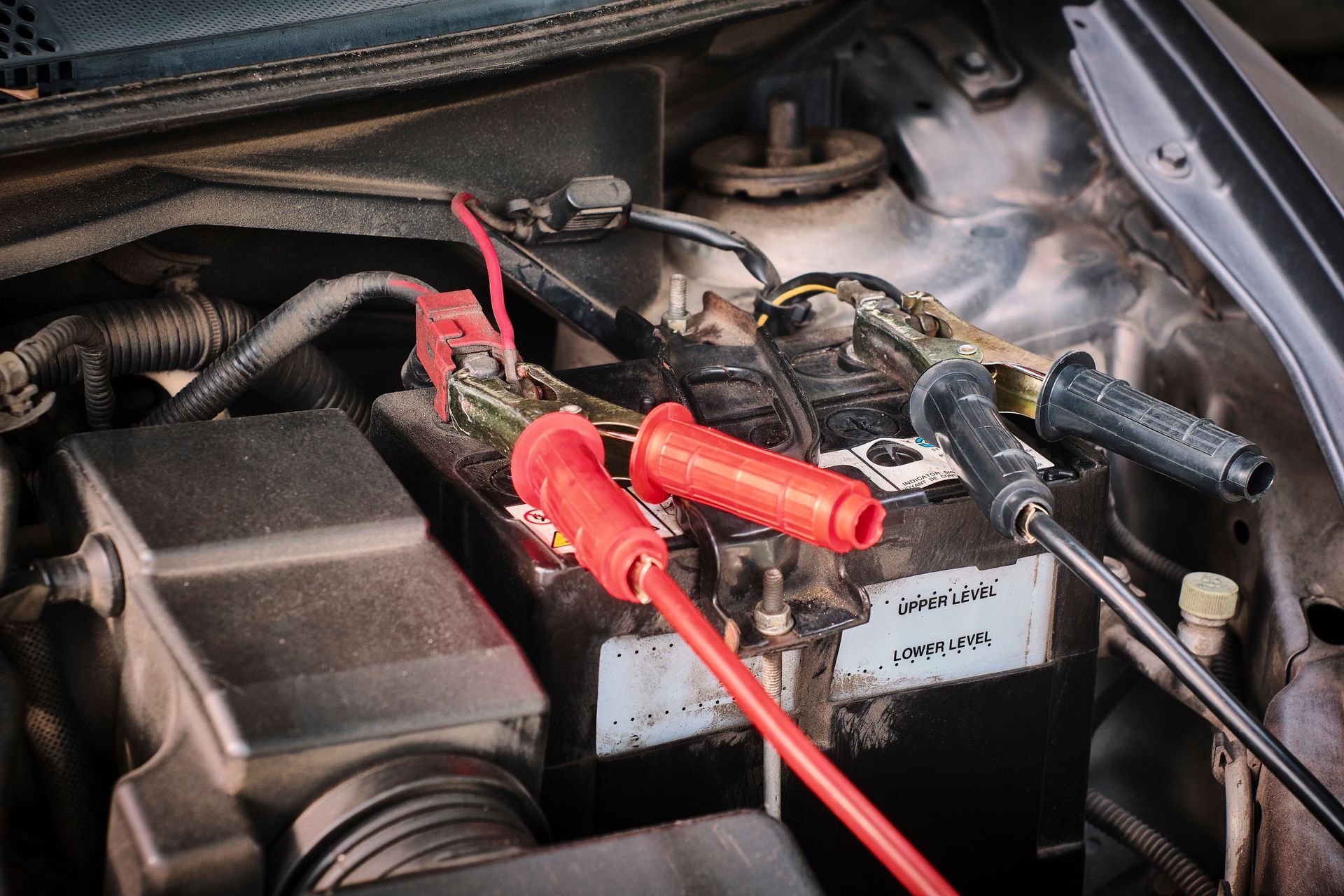 Mechanic working under a car on a lift, using a wrench in an auto repair shop.