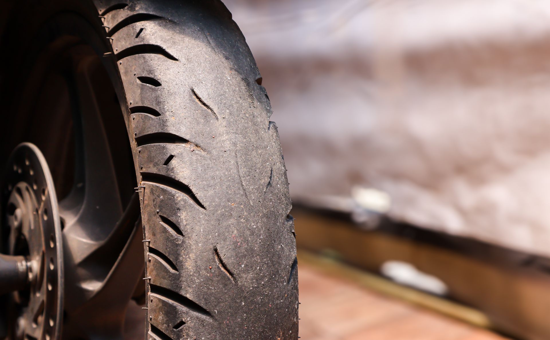 Red car lifted in a garage with tires removed and two replacement tires on the floor