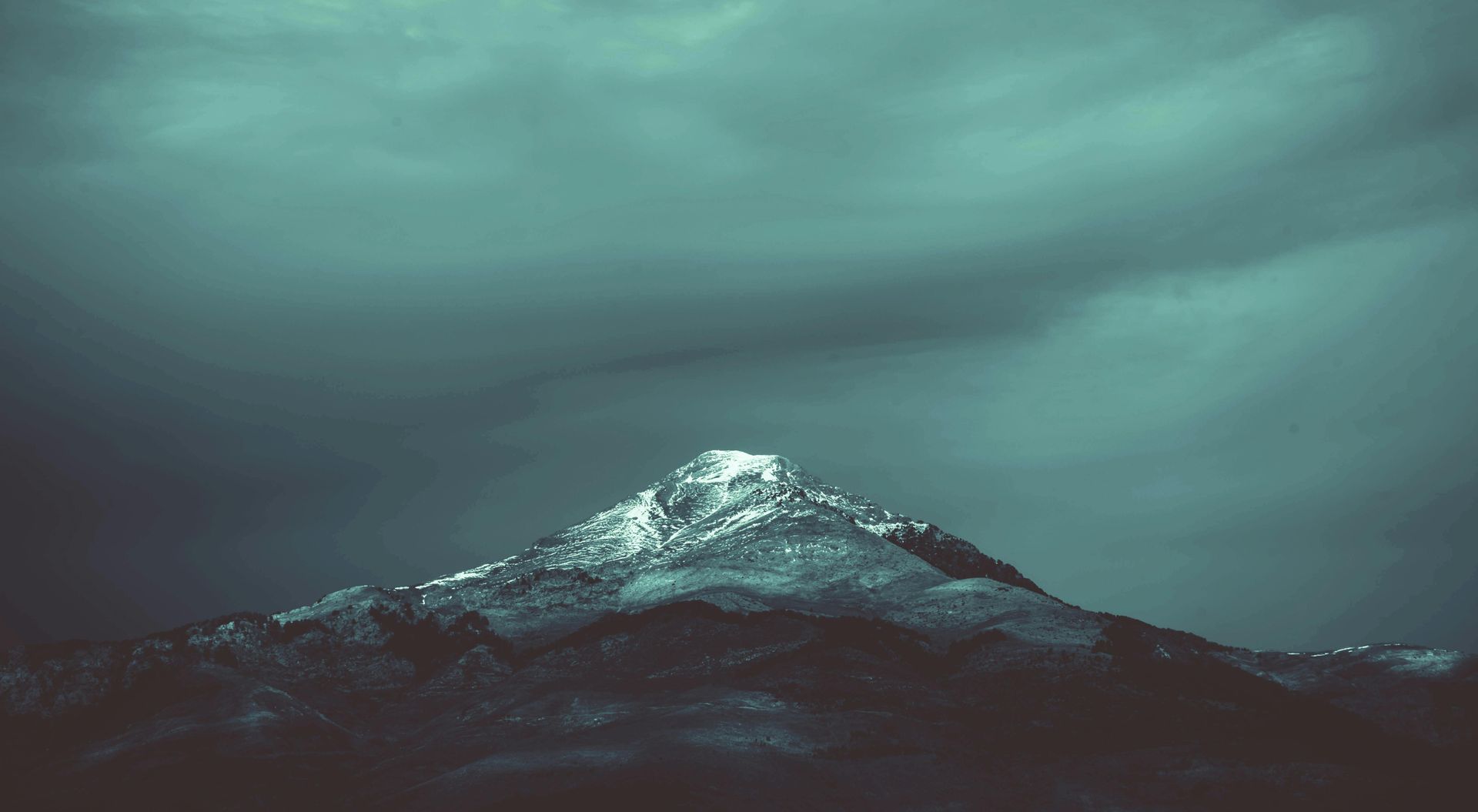 Een met sneeuw bedekte bergtop tegen een donkerblauwe lucht.