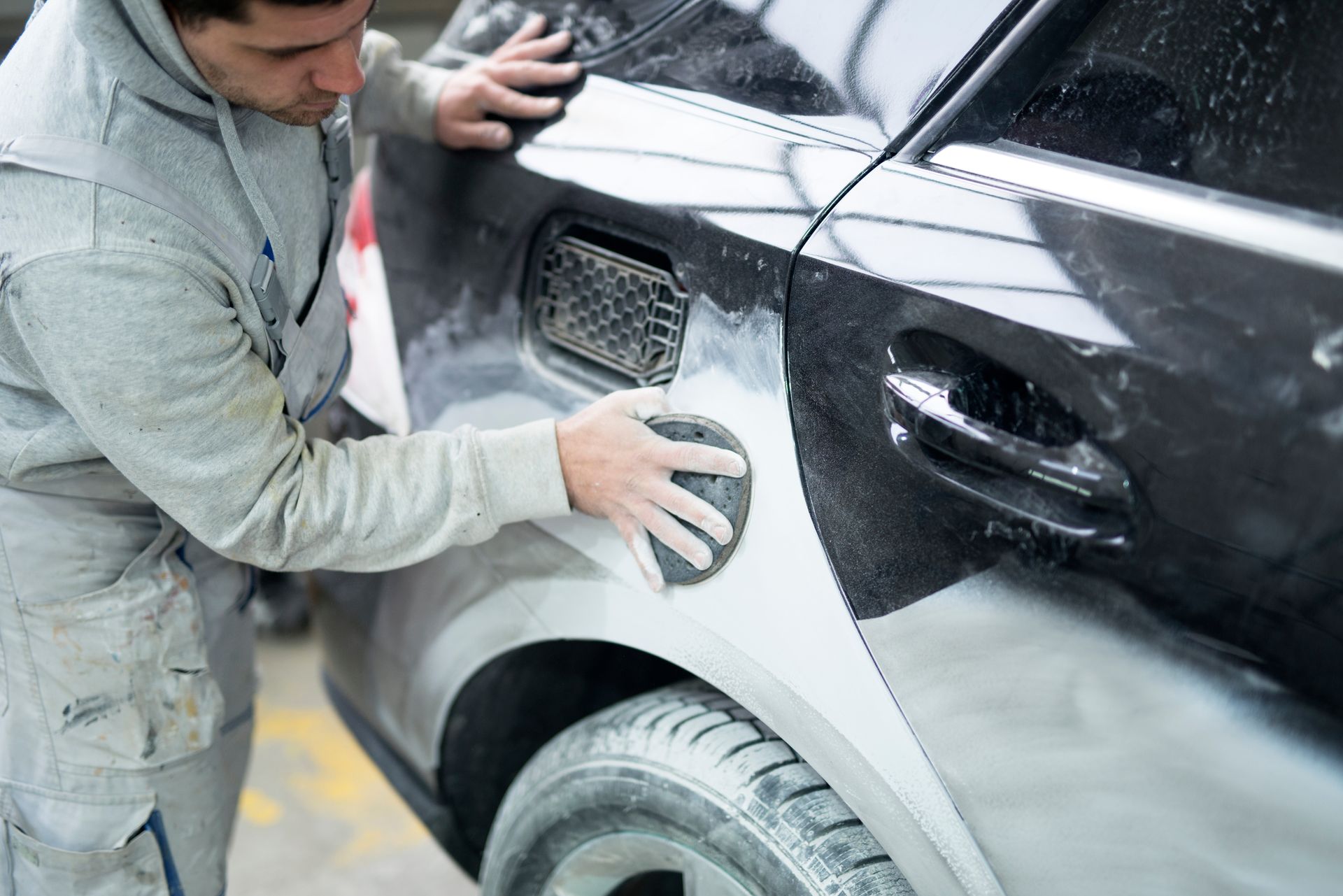 A car painter preparing a car for painting in a workshop.