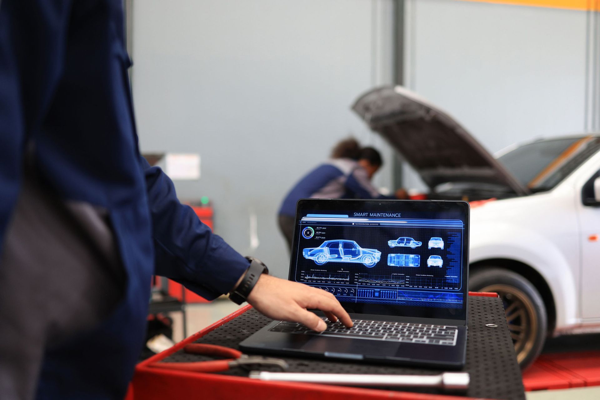 Mechanic uses laptop to diagnose car in a repair shop.