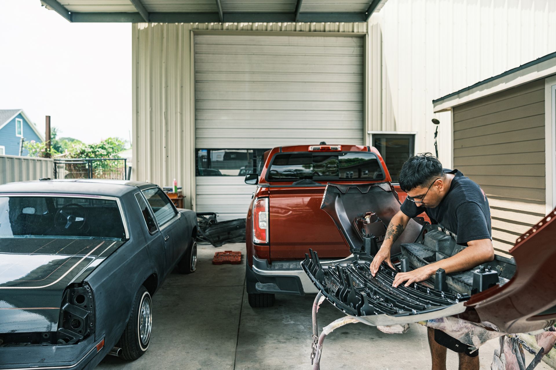 A man at an auto body repair shop performing car repairs with tools and equipment around him. A man at an auto body repair shop performing car repairs with tools and equipment around him.