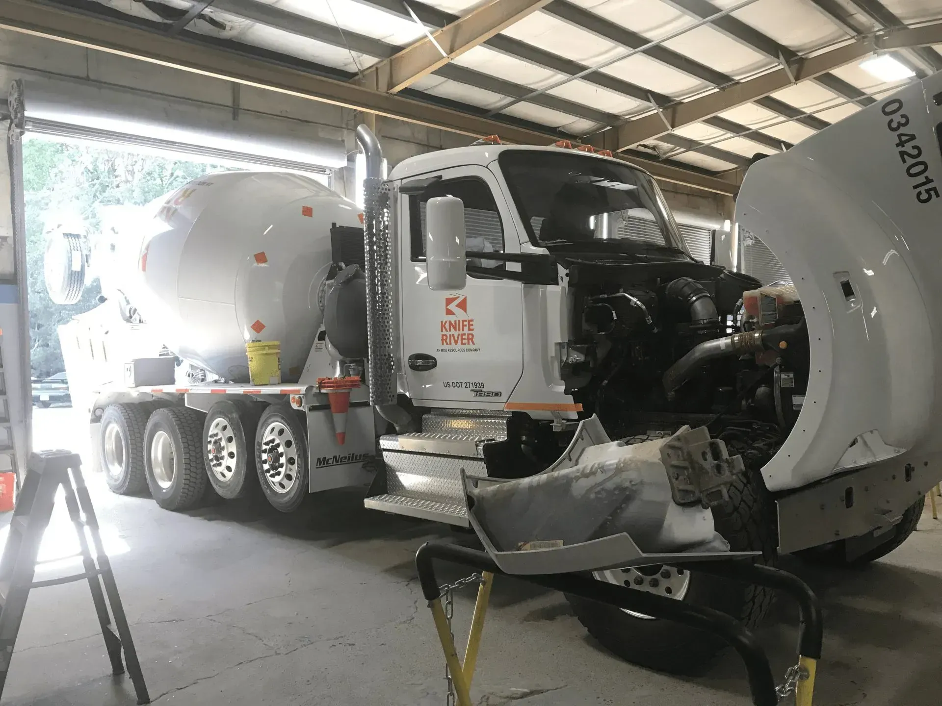 Cement truck parked in a garage with its hood open for maintenance.