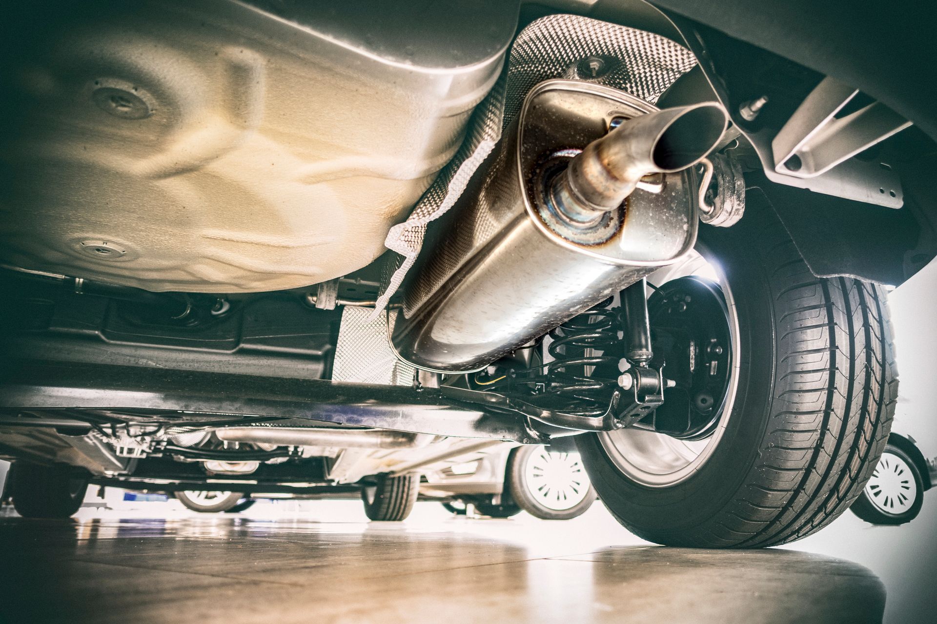 Undercarriage of a vehicle showing the exhaust system, muffler, and a tire.