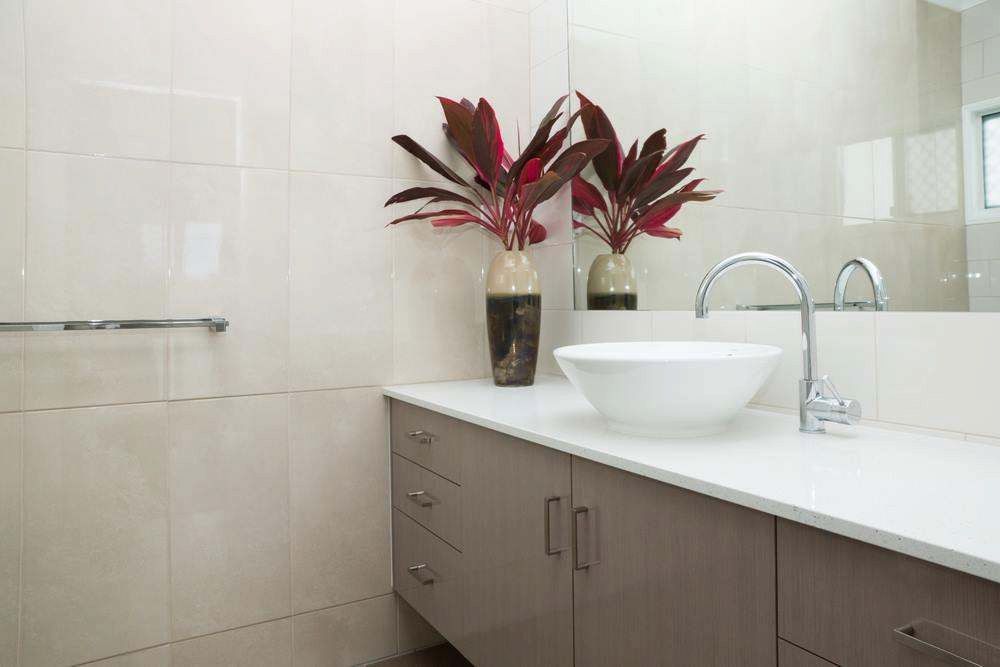 Modern Bathroom With White Vessel Sink, Chrome Faucet, and Red Plants on a Gray Vanity — Firm Built Bathrooms in Illawarra, NSW